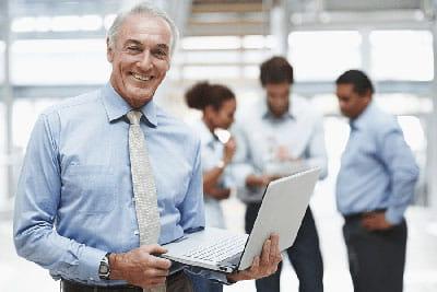 man in business office environment holding laptop